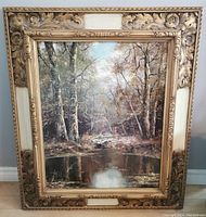Front view of large vintage oil painting reproduction in ornate gold frame showing forest and river scene