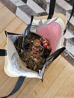 Top-down view inside the reusable bag showing an abundance of tangled scrap and broken jewelry pieces in various colors and materials.