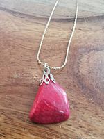 Close-up of the red gemstone pendant on the wooden surface.