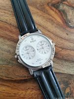 Close-up of watch face showing dual dials labeled LOCAL TIME and HOME TIME, Rojas branding, quartz movement, and water resistance indication.