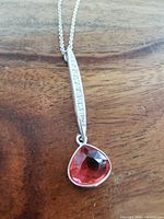 Close-up of pink faceted Swarovski crystal pendant set in silver-tone metal with embedded clear crystals on the pendant bar.