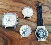Photo of all four watches on wooden surface showing details of faces and overall condition