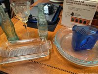 Photo showing all items including two vintage glass bottles, one etched glass wine goblet, clear rectangular serving tray, cobalt blue milk pitcher, and two clear Pyrex pie dishes.