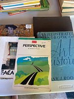Books laid flat showing art books including 'Perspective' by William F. Powell and 'An Illustrated Handbook of Art History'