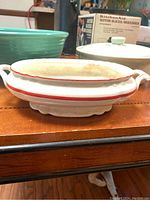 Side view of Homer Laughlin white handled serving dish with red stripe and sculpted base
