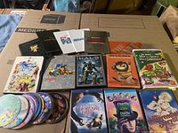 Full view of children’s movie DVDs including titles with and without covers, laid out on a surface.