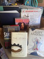 Photo of lot showing seven hardcover books including Gray's Anatomy, The Ultimate Motorcycle Book, Fierce Prey by John Sandford, The Story, and Howard Stern.