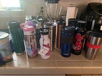 Wide shot showing all 12 bottles of varied colors, brands, and lid types on kitchen counter
