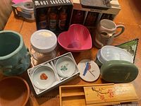 Overview of mixed kitchen and decorative items including jars, bowls, mugs, and hot sauce sets.