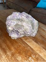 Natural amethyst stone with purple crystals and rough base sitting on a wooden surface.