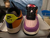 Front and rear view of the Nike Air Force One Pop The Street sneaker showing color blocking with purple, pink, orange, yellow, and black accents.