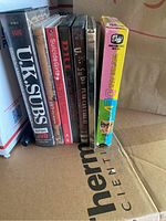 Shows seven VHS and DVD titles standing upright including U.K. Subs, Suicide Girls, D.R.I., and We're All Devo.