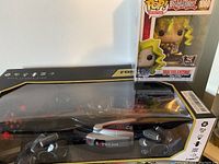 Formula One racing remote control car in original box next to Mai Valentine Funko Pop character toy in windowed box.
