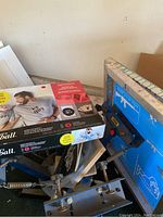 Multi-arm heat press machine with clamps and colorful frame alongside boxed Speedball screen printing stencil kit