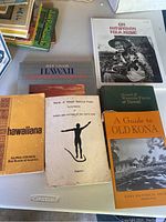 Seven books related to Hawaiian history, culture, flora, and music laid out flat on a surface.