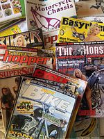 Overhead view of various motorcycle magazines displaying colorful covers with motorcycles and models, including titles such as Hot Bike, The Horse, Easyriders, and Street Chopper