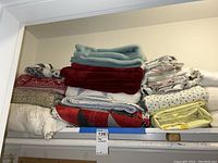Shelved folded bed linens and blankets in assorted colors and fabrics
