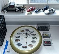 Full overview of lot on window ledge showing various boxed and unboxed model cars along with the Corvette themed clock.