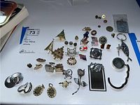 Full overview of assorted earrings, cufflinks, pins, keychains, and bookmark on table