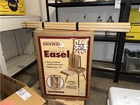 Two boxes of Mariel Studios French Style Easels with wooden parts strapped on top, front view of packaging showing specifications and image of the easel.