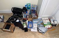 Full view of lot on floor showing assortment of men's health and beauty items including Wahl grooming machine, compression socks, blood pressure monitor, pill organizers, and back brace.