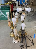 Four table lamps with different designs and materials on a concrete floor, in a garage setting