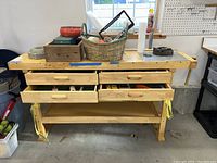 Wooden workbench with six metal drawers; drawers opened showing hand tools inside