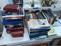 Top-down view of multiple stacked religious books including Bibles and devotional literature placed on a desk.