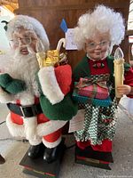 Front view of Mr. and Mrs. Claus figurines showing their detailed attire and lighted candles