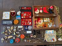 Overview photo showing the carved wood jewelry box filled and surrounded by assorted vintage pins and jewelry pieces spread on table