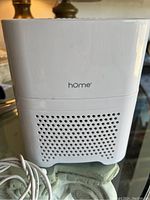 Front view of compact white Home air purifier with ventilation holes and brand logo.