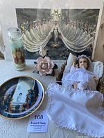 Photo showing the Precious Moments plate, baby Jesus figurine, Lord's Prayer candle, porcelain rose, and Mary print arranged on a white surface