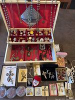 Full lot overview showing large open jewelry box with multiple religious crosses, medals, rosary beads, and smaller boxes containing more items arranged below it.