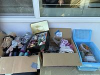 Photo showing multiple boxes and baskets filled with assorted sewing threads, ribbons, and fabrics.