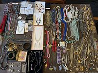 Overhead view of entire assortment laid out on table showing necklaces, bracelets, earrings, pendants and brooches