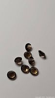 Close-up image showing 10 faceted round cut natural smokey quartz gemstones with a translucent brown color and reflective surfaces.