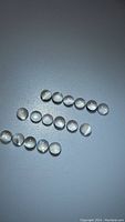 Multiple small calibrated round moonstone cabochons with visible cat's eye effect, arranged on plain background.