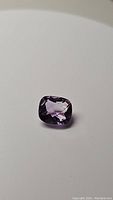 Photo of 3.76 carat cushion checkerboard cut purple amethyst gemstone on white background, showing color and clarity.