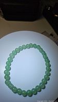 Photo of a natural green aventurine bead bracelet laid flat in a circular shape showing polished round beads.