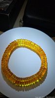 Photo of golden Baltic amber stretchy bracelet shown coiled on white surface with black background.