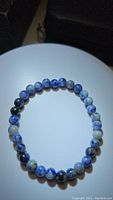 Photo of a natural sodalite stretchy bracelet with round blue and white patterned beads on a white circular stand.