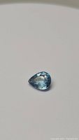 Pear-shaped deep blue aquamarine stone with visible internal inclusions on white background.