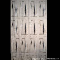 Full length of vintage 1950s rayon fabric hung up to show scale and overall printed geometric pattern in blue, gold, and black on cream background.
