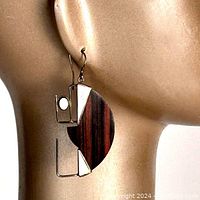 Side profile of the earring on a mannequin ear showing the curved rosewood, geometric sterling silver framing, and natural white stone inset.