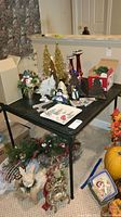 Black folding card table shown with various Christmas decorations and boxes on and around it, illustrating table size and condition.