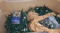 Sterilite bin full of assorted Christmas lights with bundles of green wire strings and packaged lights on top.