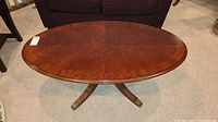 Top front angled view of oval wooden coffee table showing polished surface and oval shape.