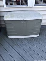 Full view of Rubbermaid deck box placed on a wooden deck against siding, showing size and condition.