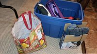 Photo of exercise bands, yoga mat, and other items stored inside blue plastic bin and a white reusable bag adjacent.