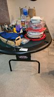 Poker table showing the top surface with various items on it, demonstrating the table's cushioned edge and general size.
